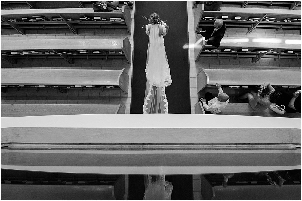 A high angle shot of a bride walking into the church with her bridal gown behind her