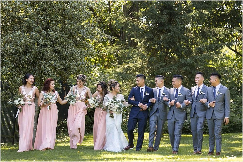 a bridal party walk together arm in arm at Deer Lake Park in Burnaby, BC