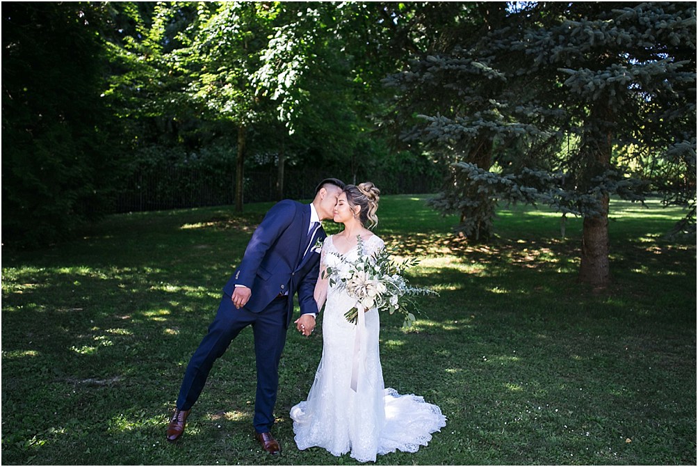 a groom leans over and kisses his bride on the cheek